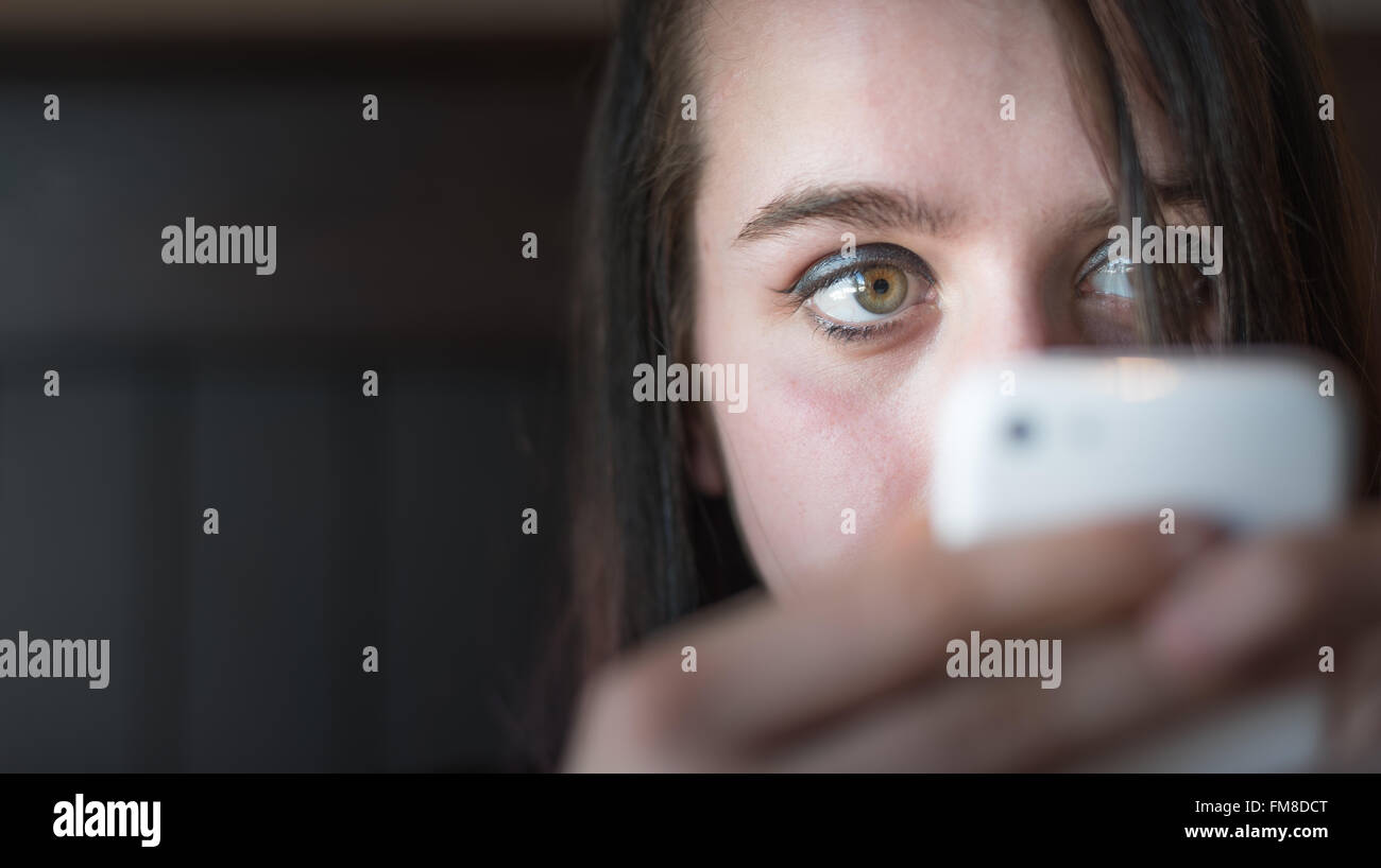 Young woman looking at her cell phone while using it. Girl talking to ...
