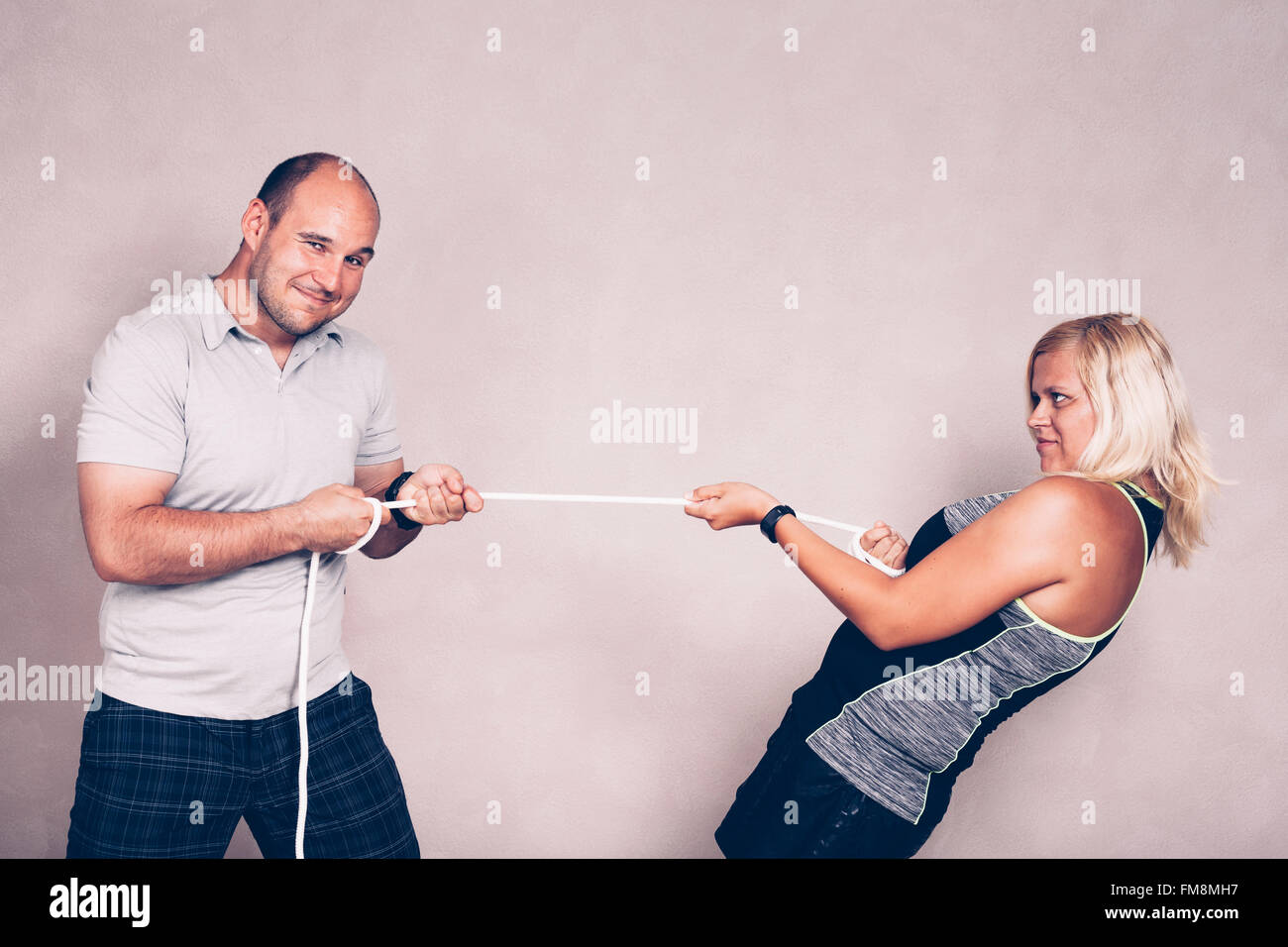 Positive confident sporty man and woman pulling a rope. Competition, confidence and effort concept. Stock Photo