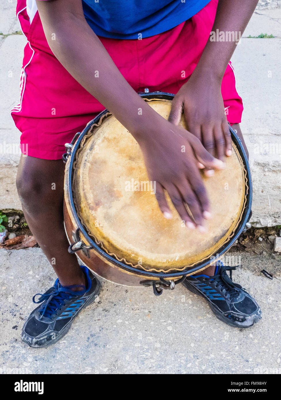 Cuban boy playing drum outside his house on the street in the town of Regla across the harbor from Havana, Cuba. Stock Photo