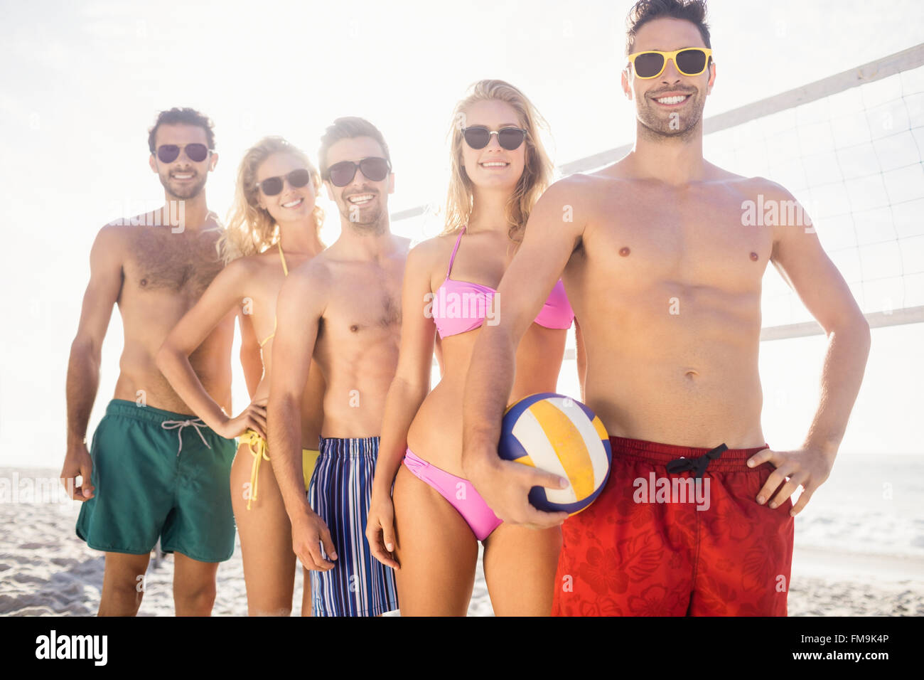 Smiling friends in line after playing volleyball Stock Photo
