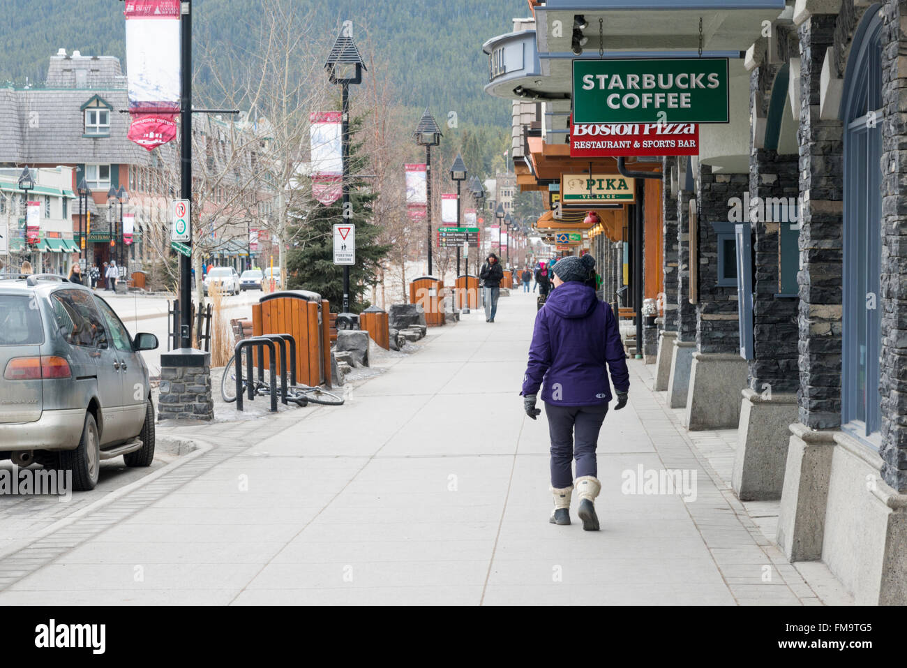 A shopper walking in Banff Avenue Banff Canada by Starbucks and tourist shops Stock Photo