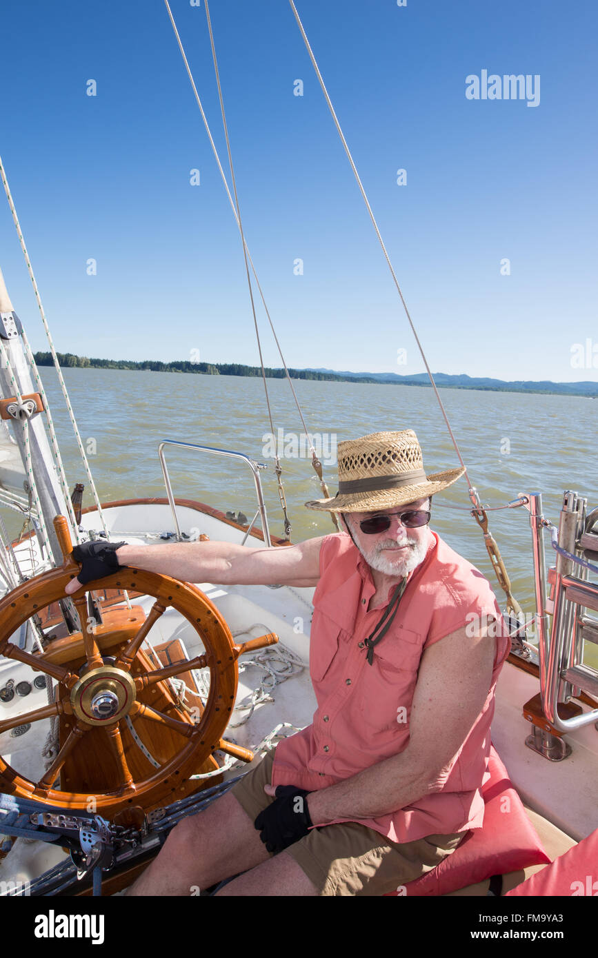 A senior man at the helm of sailboat navigates on Fern Ridge Reservoir