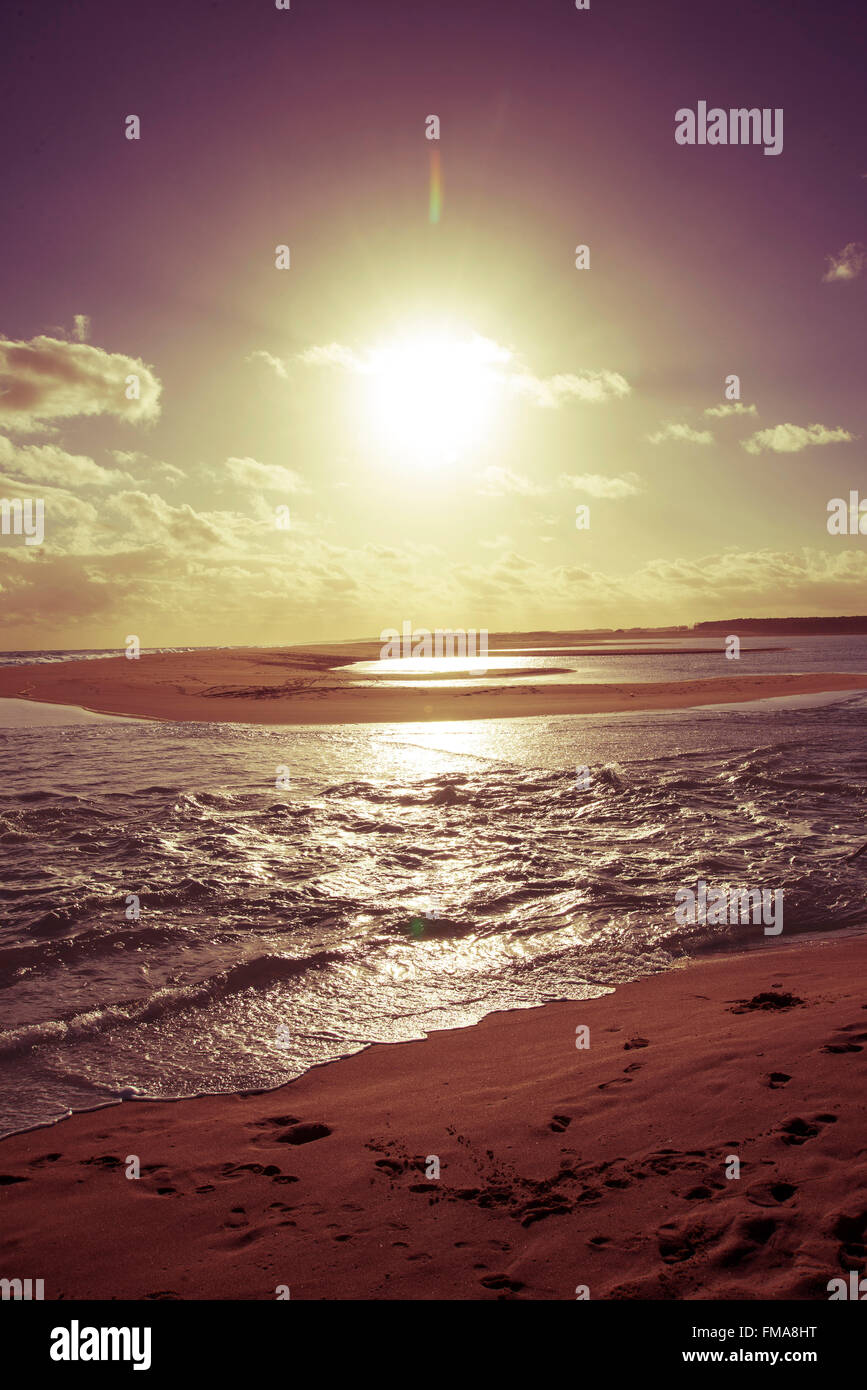 Vintage style reflecting sun on the sea shore beach landscape, footprints in the sand. Stock Photo