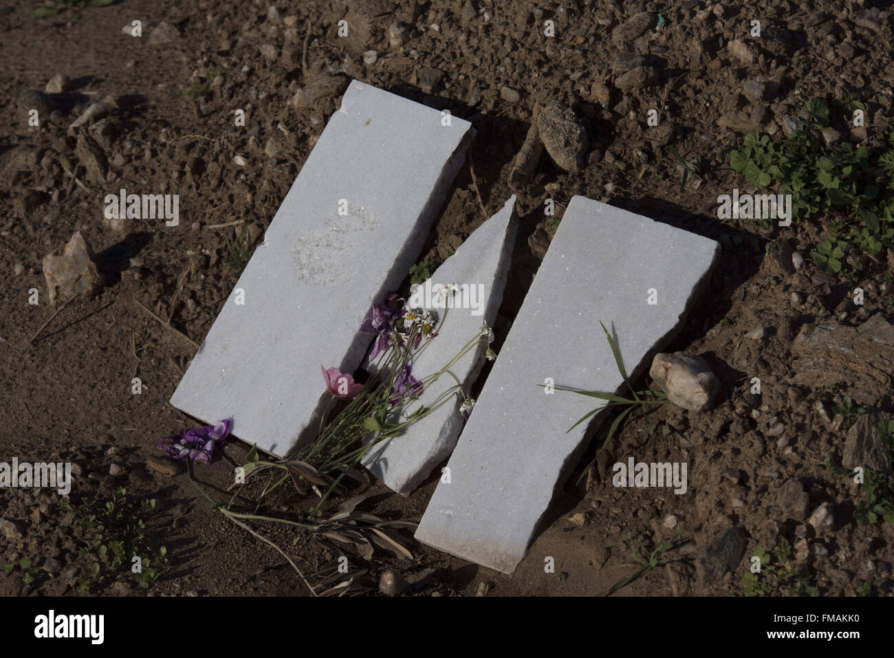 Lesvos, Greece. 11th Mar, 2016. Flowers are laid on a broken tombstone on a grave at a makeshift cemetery for refugees in Lesvos reads, . Nearly 3,000 people, many of them women and children have died during 2015 trying to cross from Turkey to Greece. Credit:  Nikolas Georgiou/ZUMA Wire/Alamy Live News Stock Photo