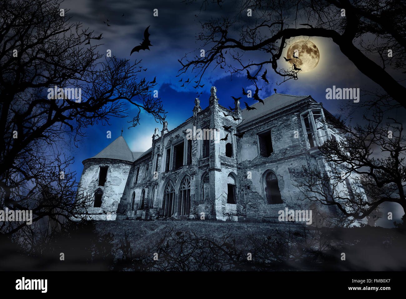 Haunted house in creepy foggy background with tree silhouettes. Stock Photo