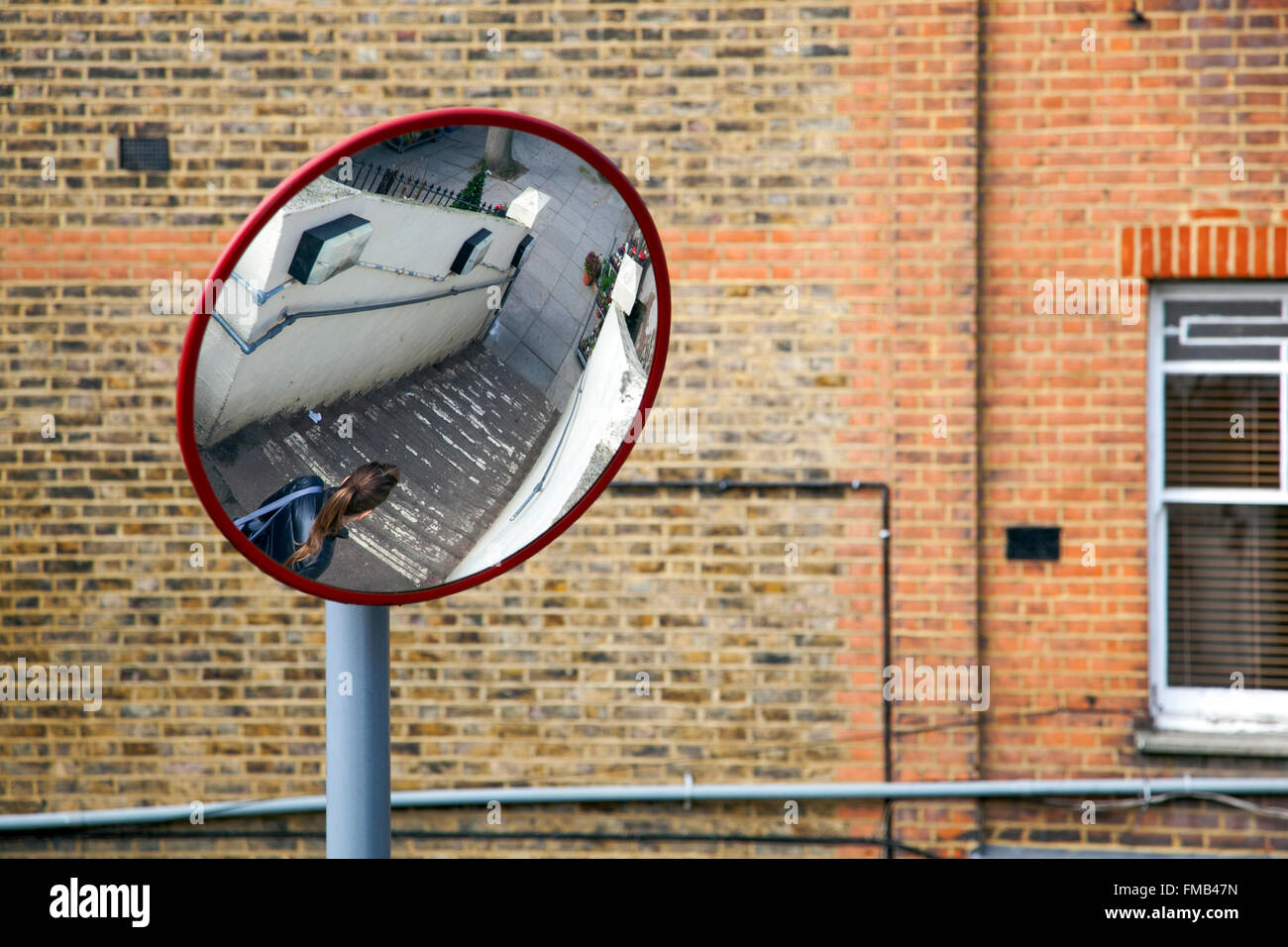 Safety convex mirror reflection a woman walking down the stairs in a public space with low visibility Stock Photo