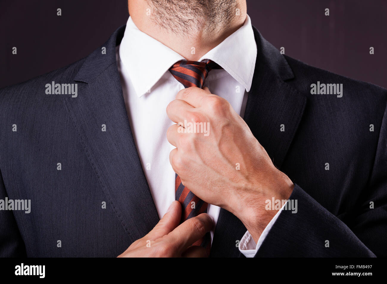 Man in a suit fixing his tie on grunge background Stock Photo - Alamy