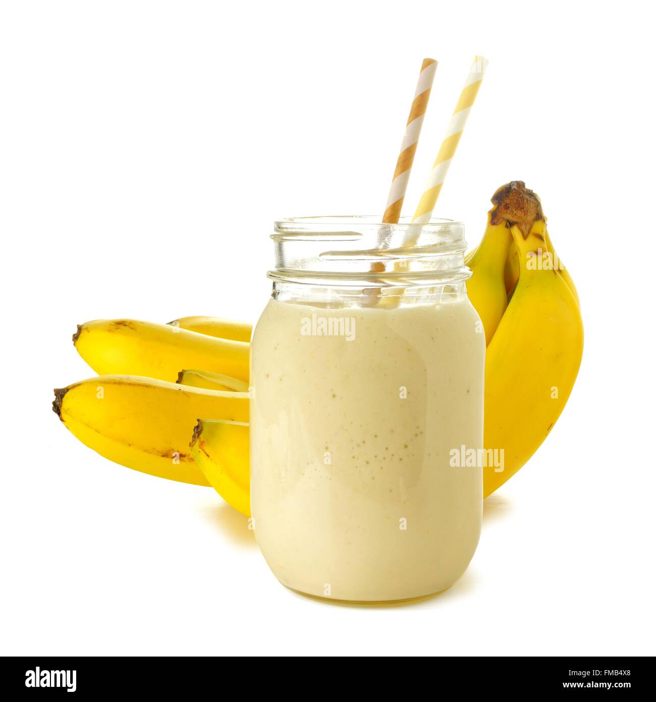 Banana smoothie in a jar with straws over white, bananas in background Stock Photo