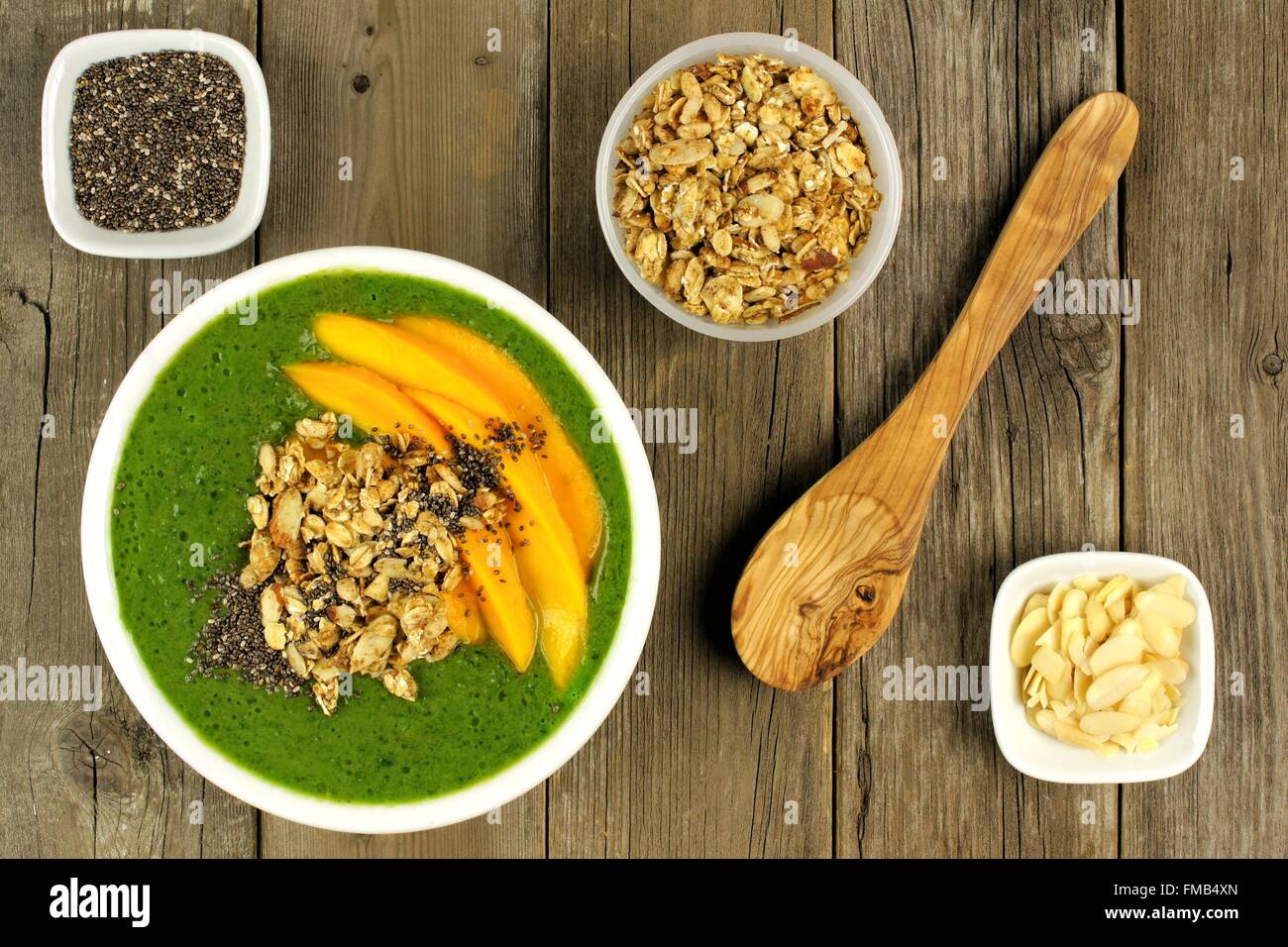 Green smoothie bowl with mangoes, granola, almonds and chia seeds