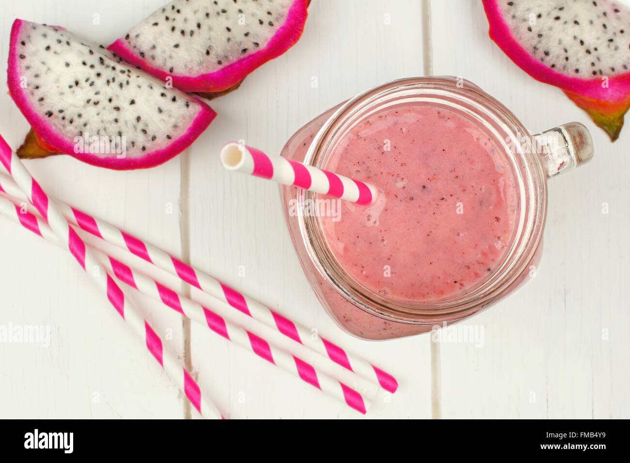 Pink raspberry, dragon fruit smoothie with fruit slices and straws on a white wood background, downward view Stock Photo