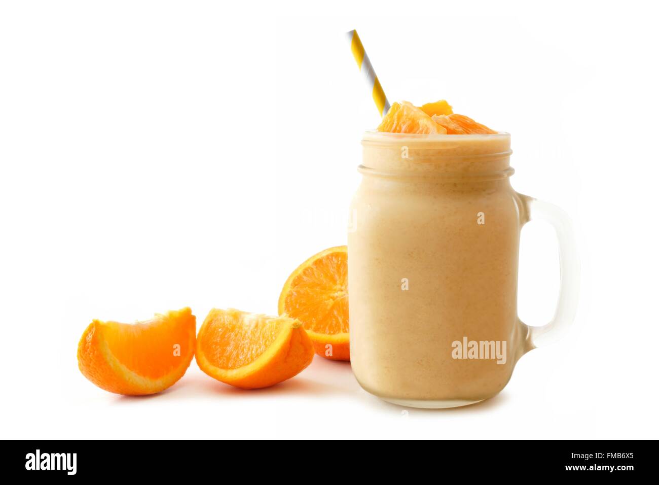 Orange smoothie in a mason jar glass with striped straw and fresh fruit slices isolated on white Stock Photo