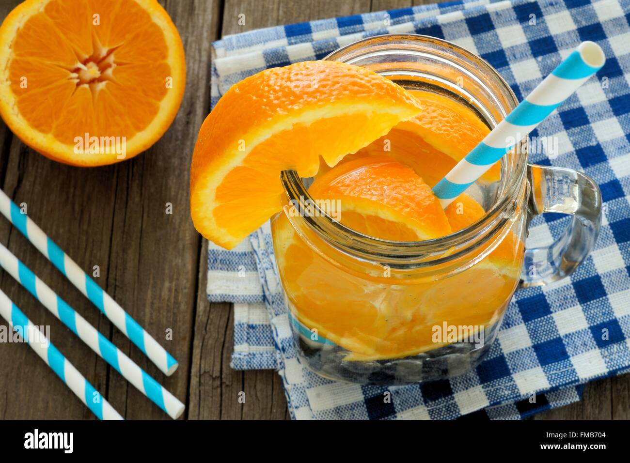 Detox water with oranges and blueberries in a mason jar with straw. Downward view on wood with checkered cloth. Stock Photo