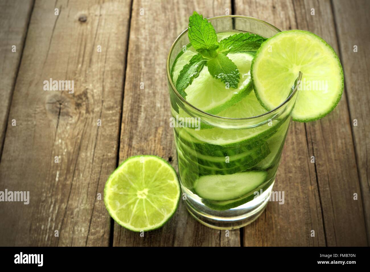 Healthy vitamin water with lime and cucumber in a glass against and rustic wood background Stock
