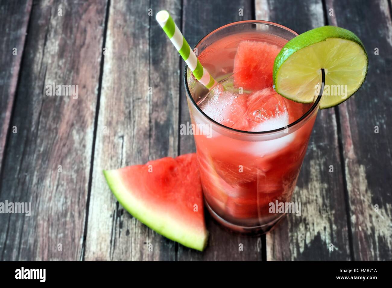 Watermelon lime water in a glass with melon slice and straw against white rustic wood background Stock Photo