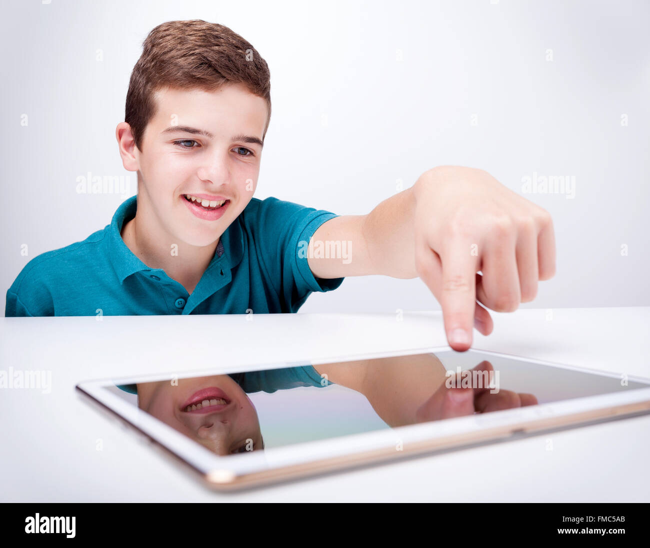 Teen boy playing with a tablet computer against gray background Stock ...