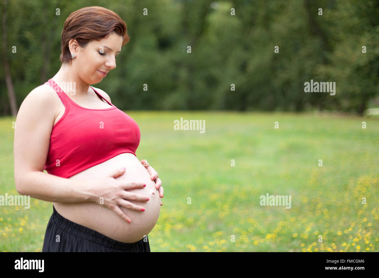 Pregnant woman holding her belly outdoors Stock Photo - Alamy