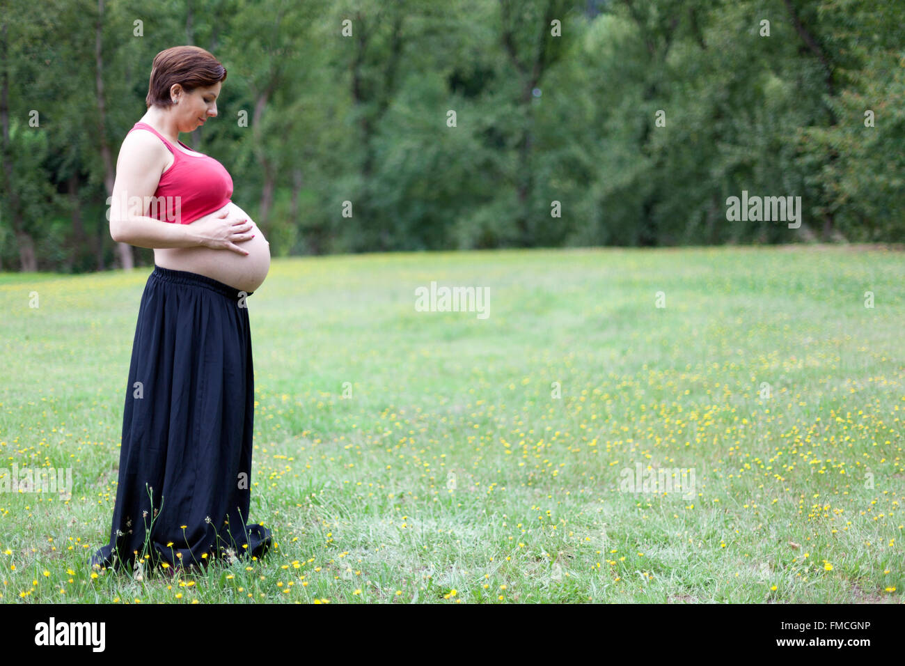 Pregnant woman holding her belly outdoors Stock Photo - Alamy