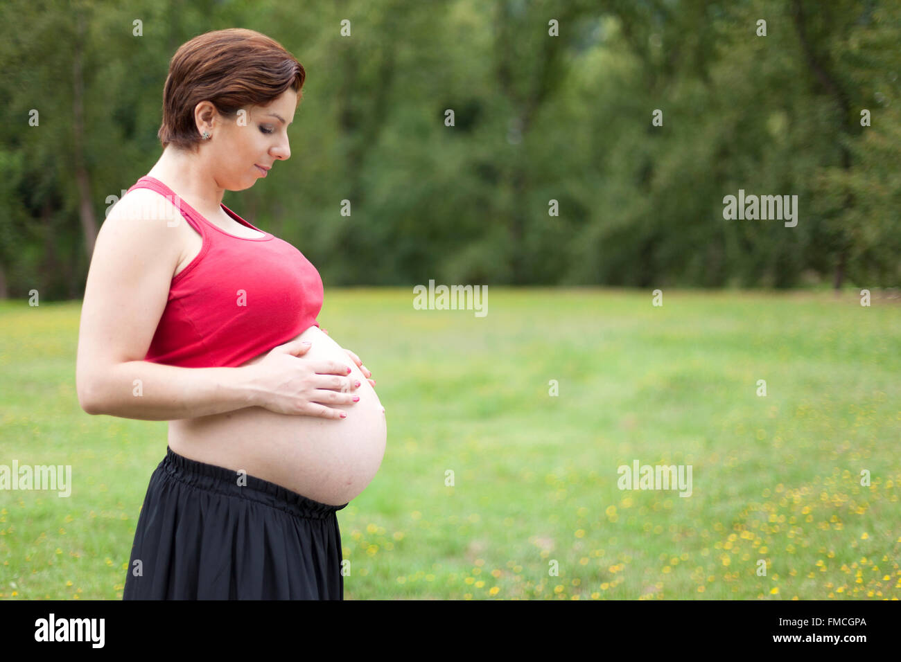 Pregnant woman holding her belly outdoors Stock Photo - Alamy