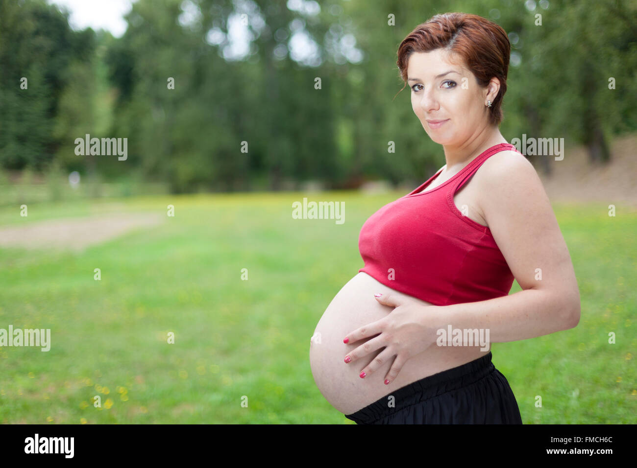 Pregnant woman holding her belly outdoors Stock Photo - Alamy