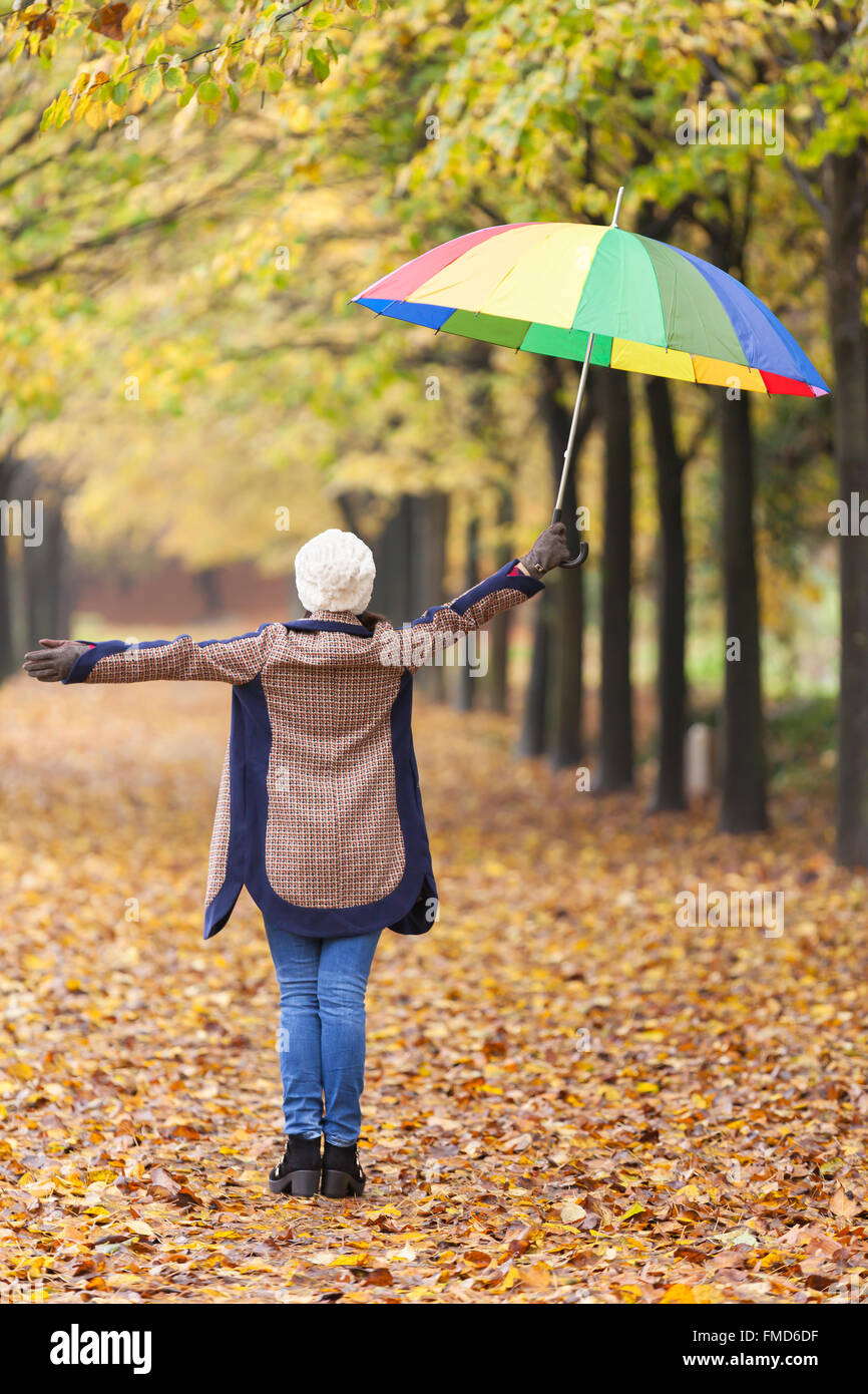 Woman walking with colorful umbrella at the park Stock Photo - Alamy