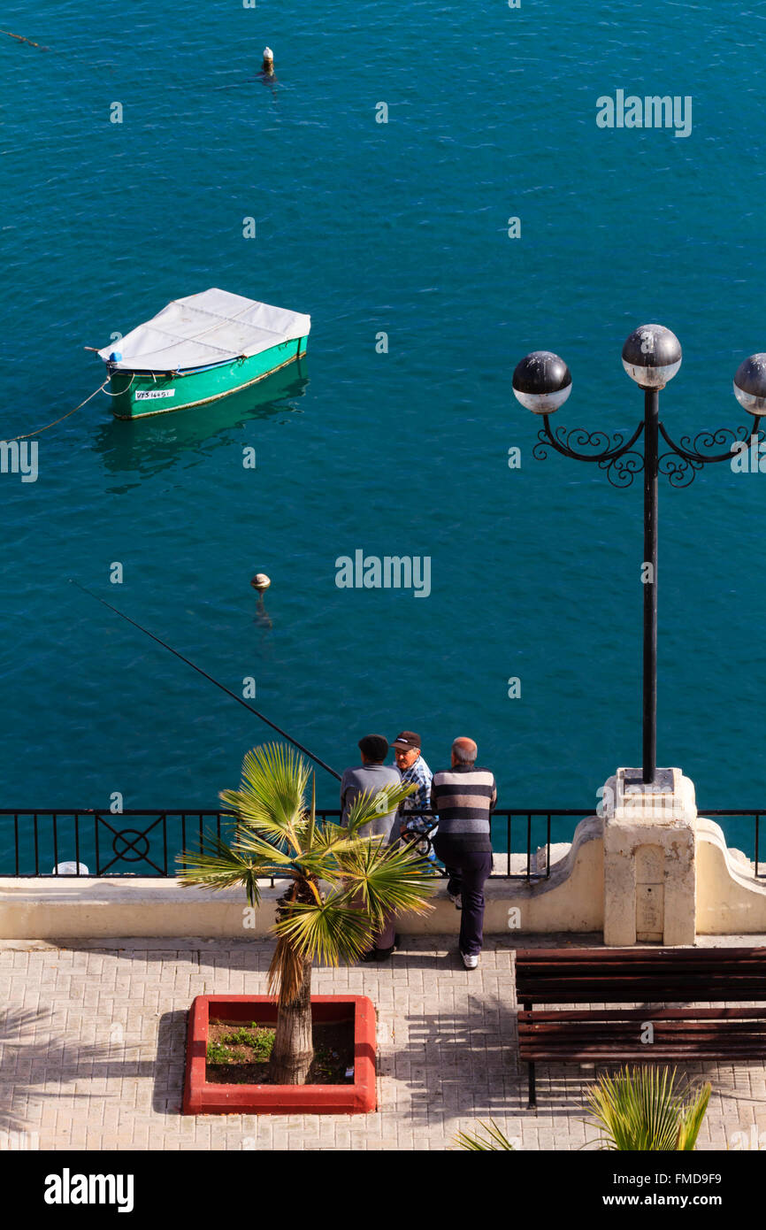 Local Maltese men fishing from the promenade, Sliema, Valletta, Malta. Stock Photo