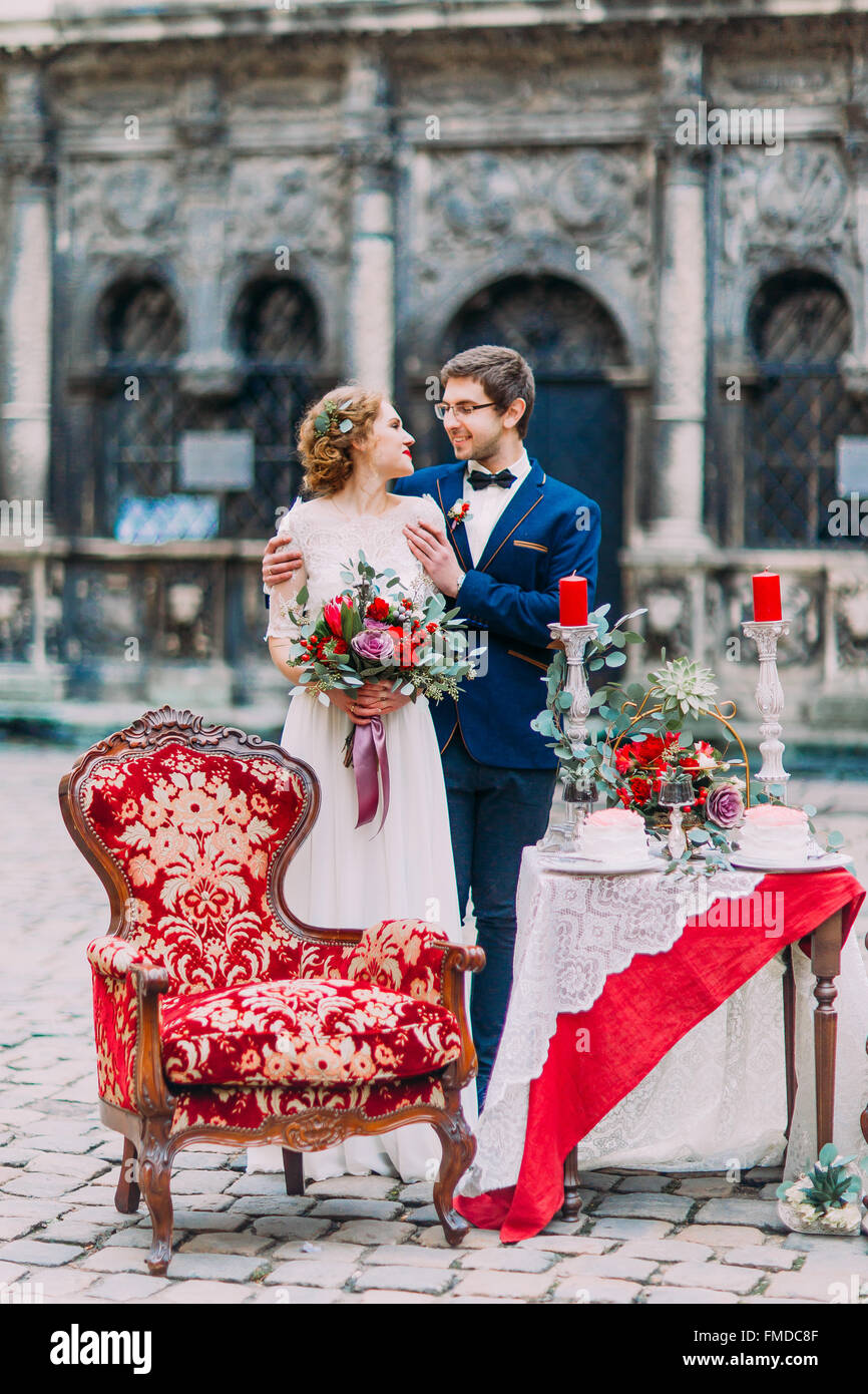 Cheerful newlyweds softly look at each other with the table setted for ...