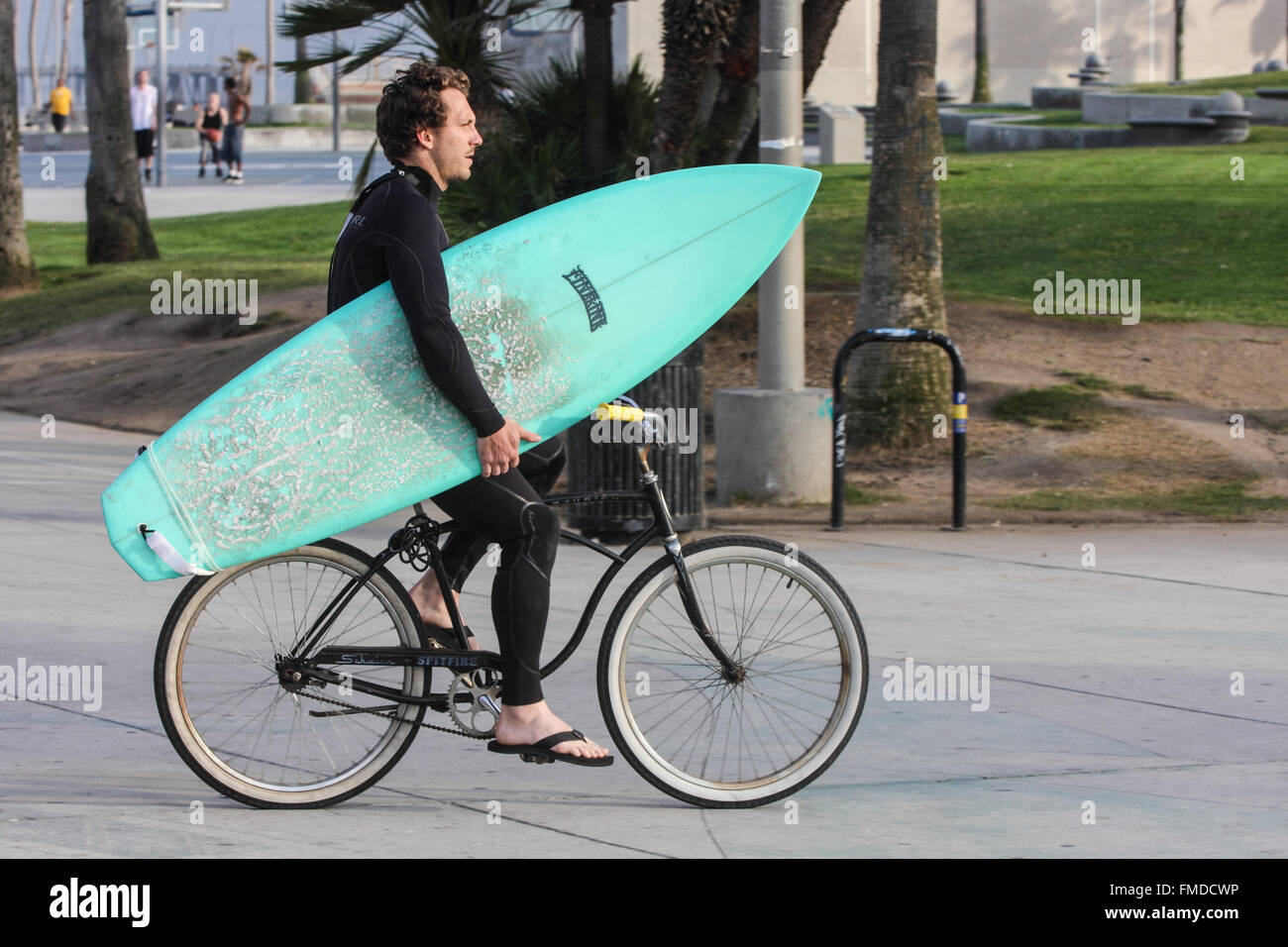 Surfer,in,wetsuit,with,surfboard,carrying,carry,on,bicycle,on,Venice Beach,Santa Monica,Los