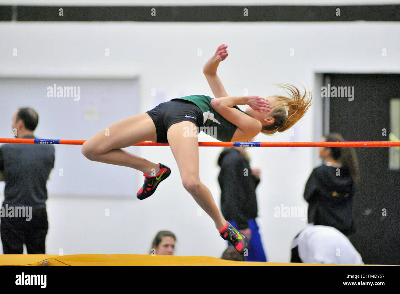 A high school athlete attempting to clear the high jump bar at an indoor meet. USA. Stock Photo