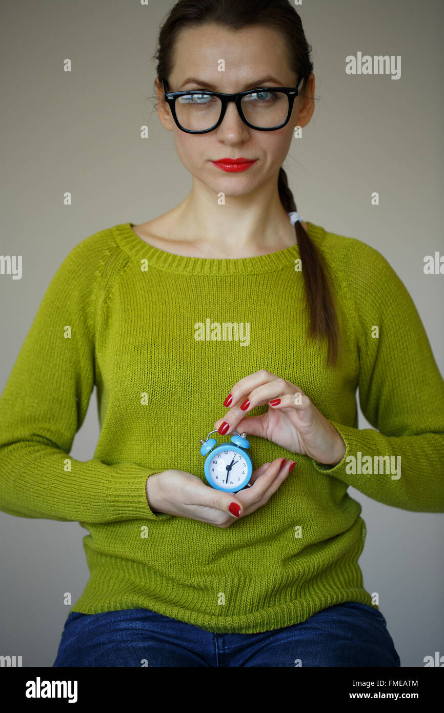 Little blue alarm clock in the hands of young woman, concept of saving time Stock Photo