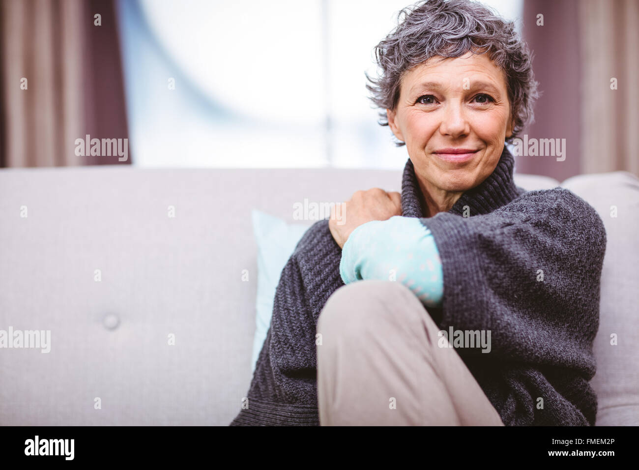 Portrait of smiling mature woman sitting on sofa Stock Photo - Alamy