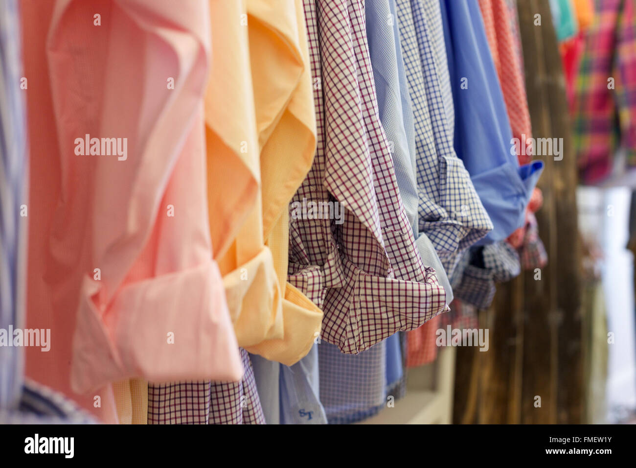 Men's cotton shirts, sleeves cuffed, hanging in a row. Stock Photo