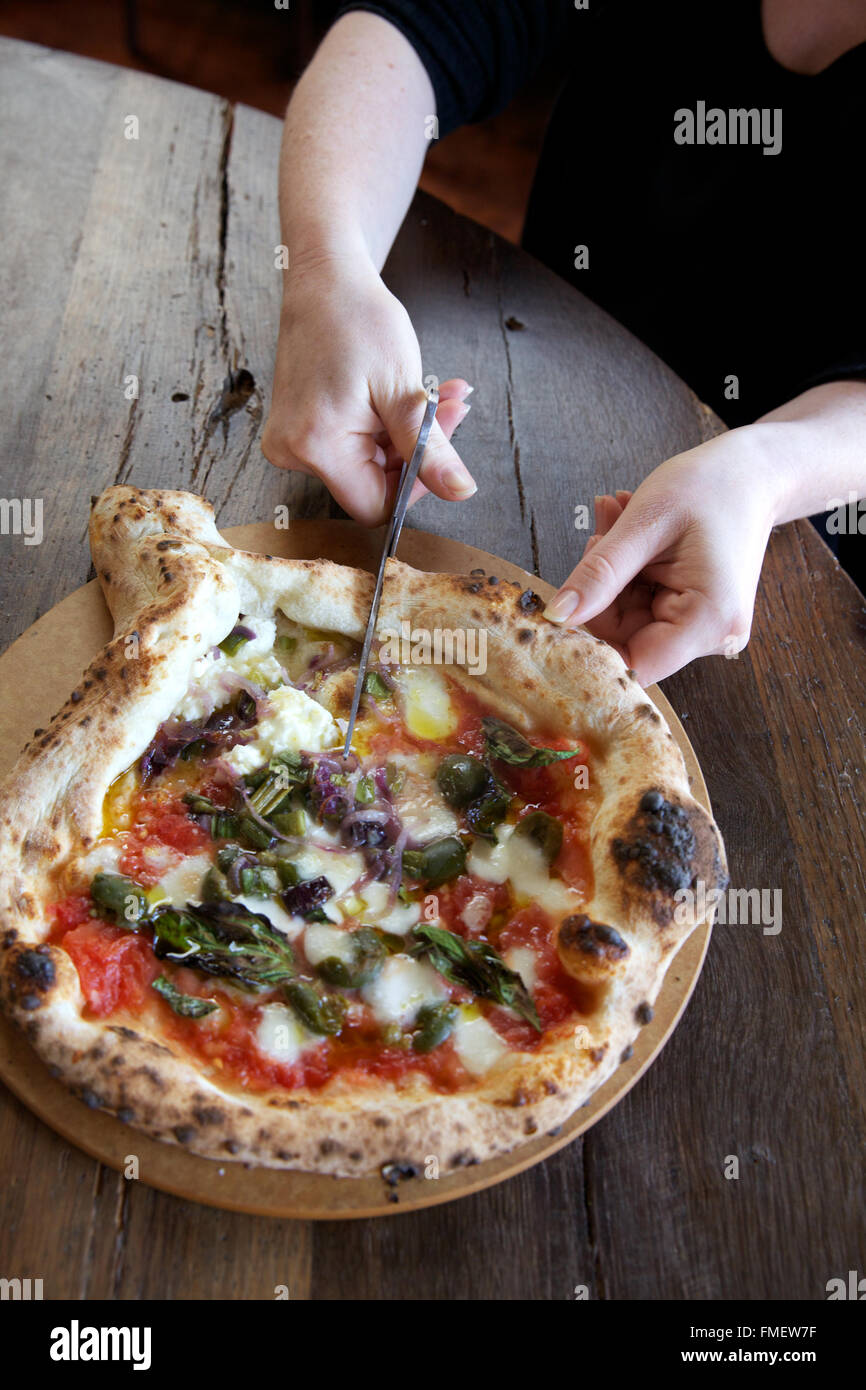 A woman cuts a Neapolitan style pizza with scissors Stock Photo Alamy