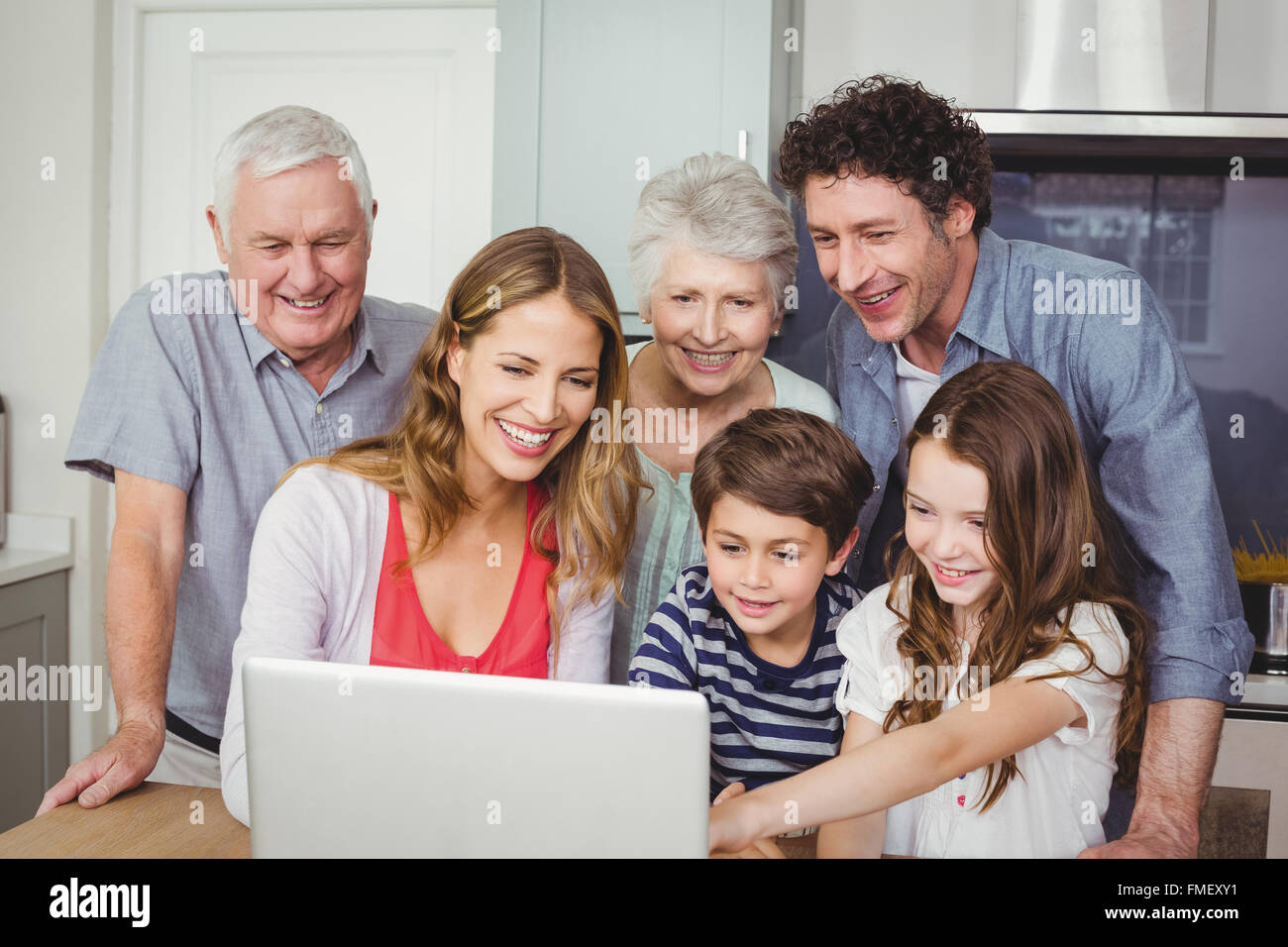 Happy family using laptop in kitchen Stock Photo - Alamy