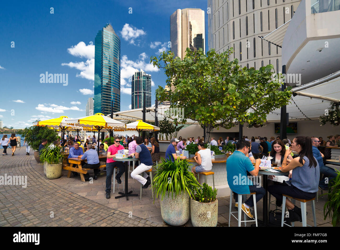 Al fresco lunchtime diners on the riverside walk at Eagle street pier Brisbane with high rise buildings / skyscrapers Stock Photo