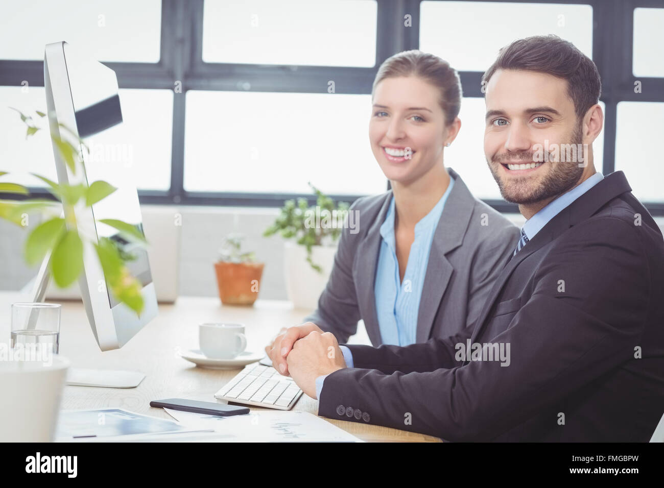 Happy business people working at computer at desk Stock Photo