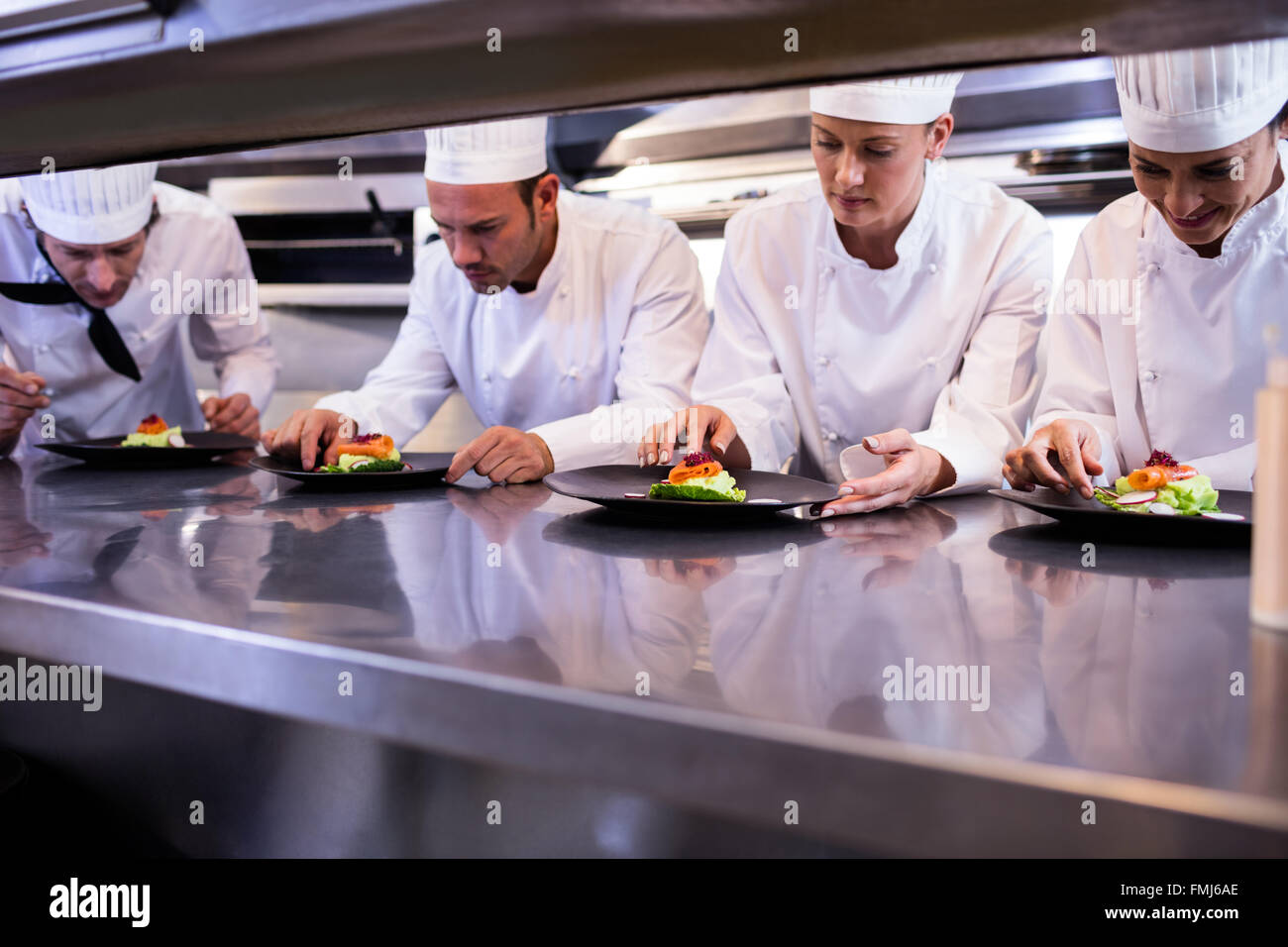 Team of chefs garnishing dishes Stock Photo
