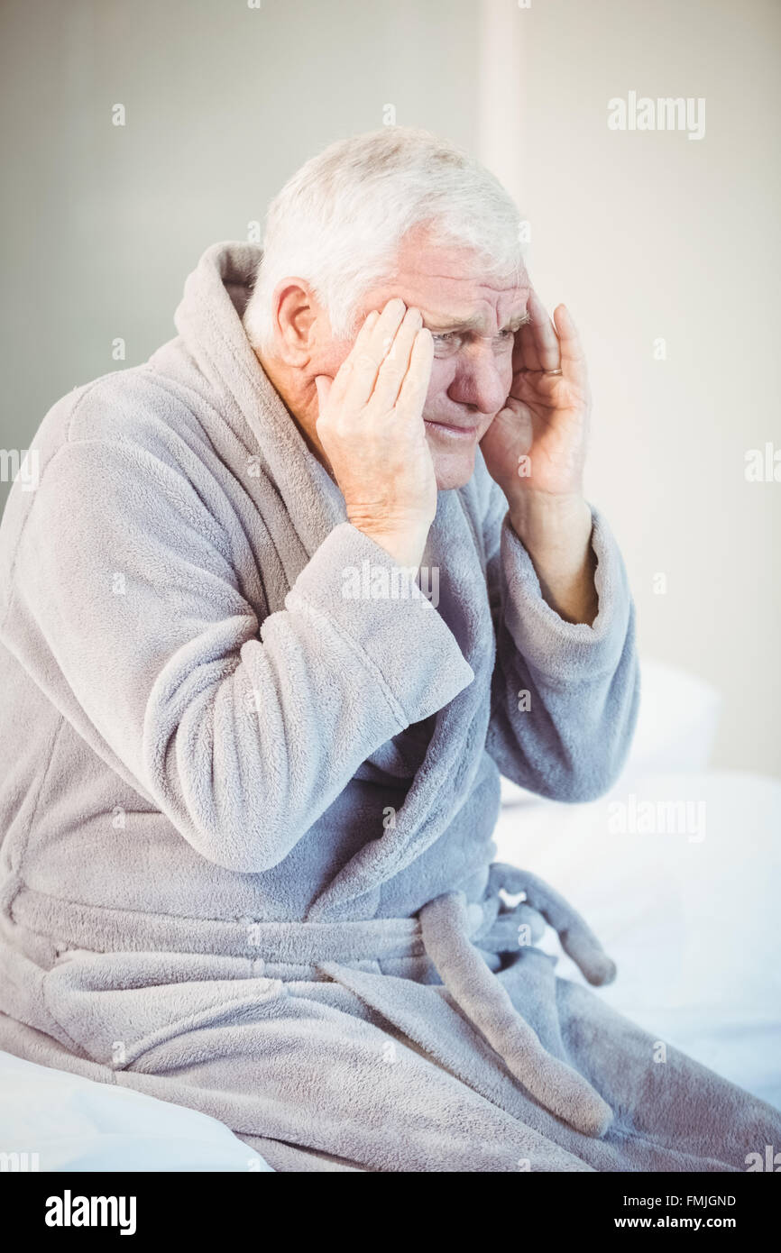 Senior man suffering from headache while sitting on bed Stock Photo - Alamy