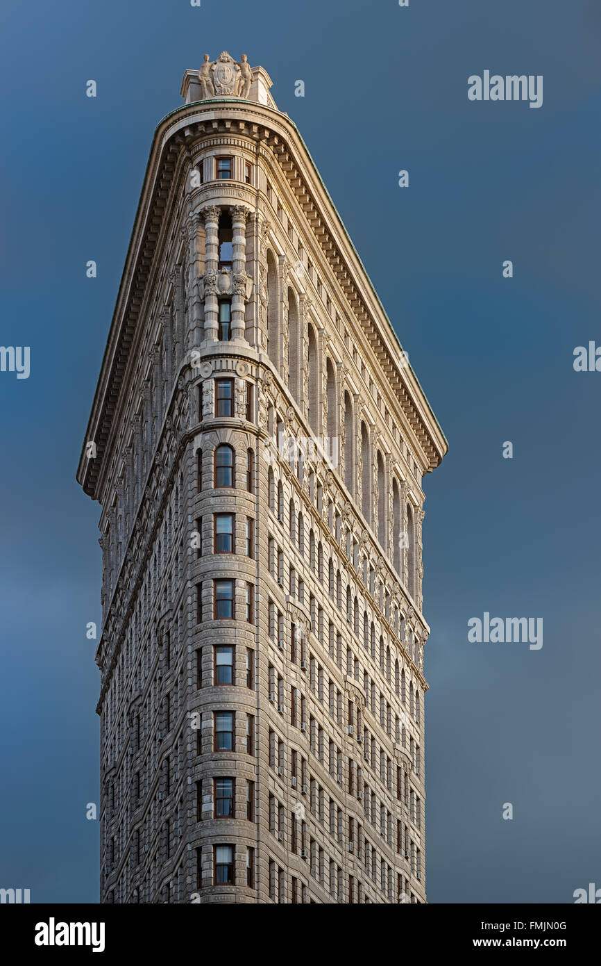 The Flatiron Building facade lit by afternoon light against a stormy sky. Flatiron District, Manhattan, New York City Stock Photo