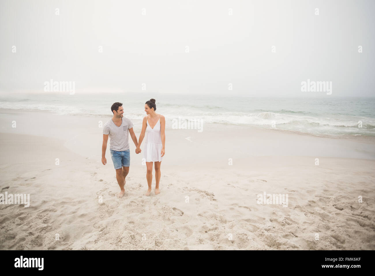 Happy couple holding hands and walking on the beach Stock Photo - Alamy