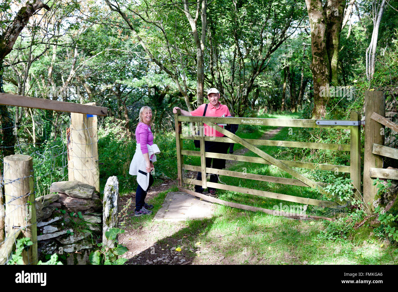 Two walkers on a footpath in the woods above Lee Abbey in North Devon, England, UK Stock Photo