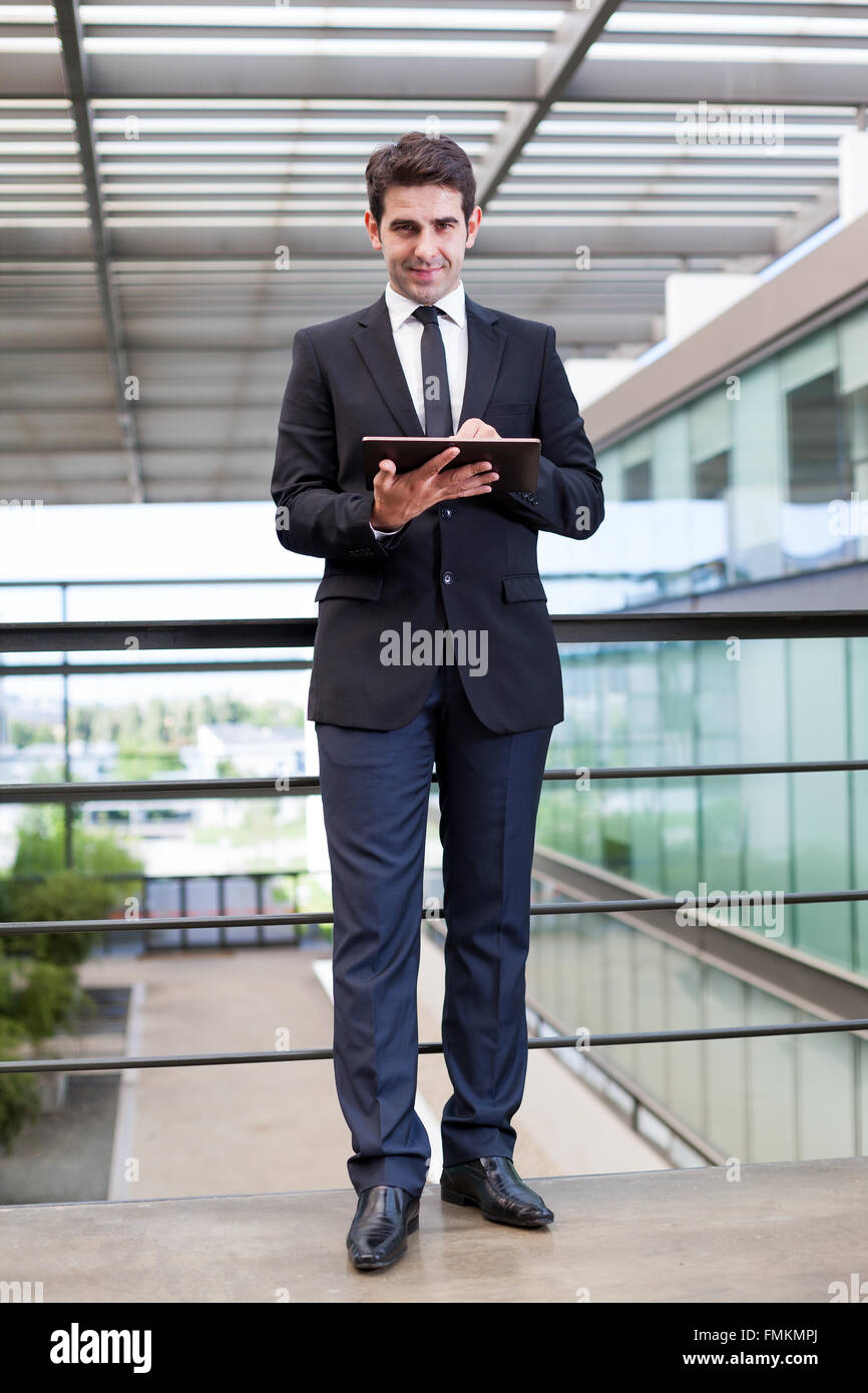 Smiling young businessman using his digital tablet at the office Stock ...