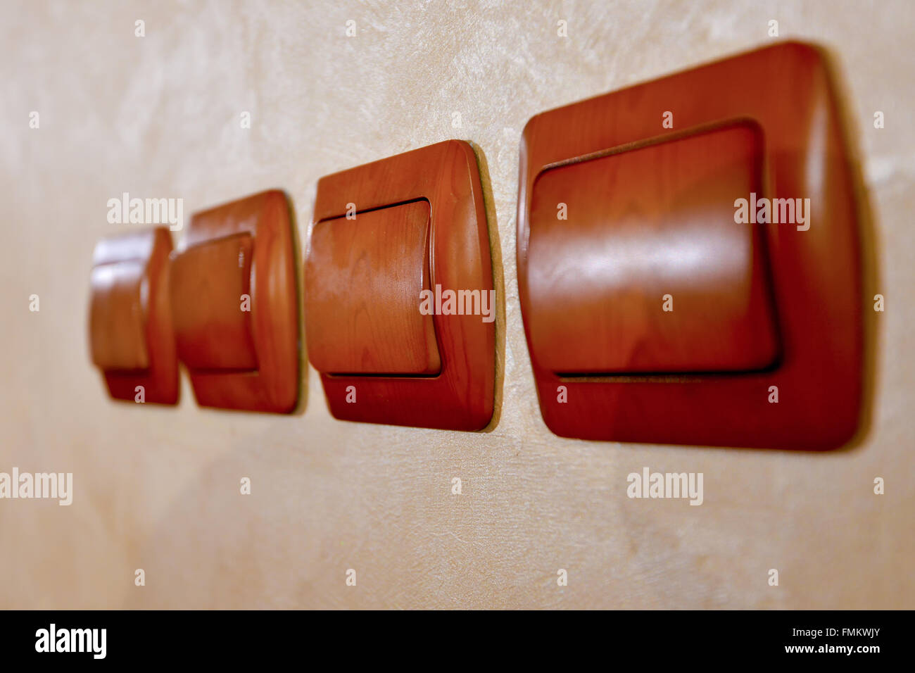 Four brown wooden switches next to wall Stock Photo