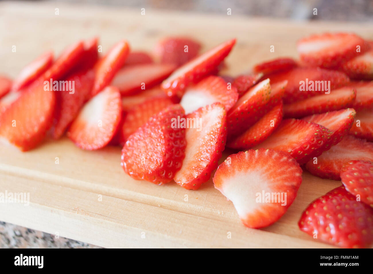 Strawberry slices on a wooden cutting board Stock Photo