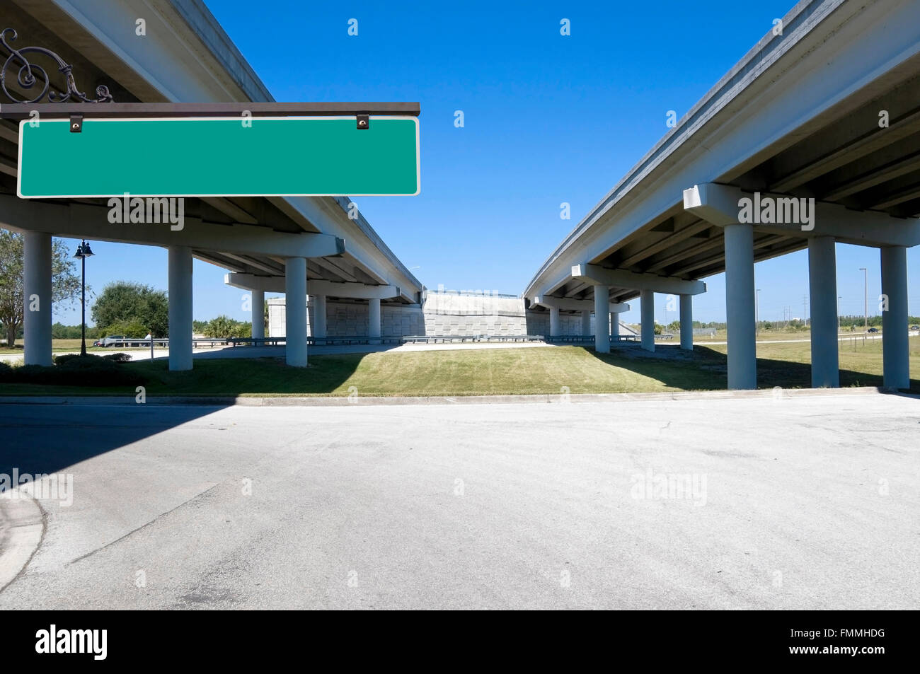 Multi-lane expressway overpass showing structural columns with blue sky with green street sign for text Stock Photo