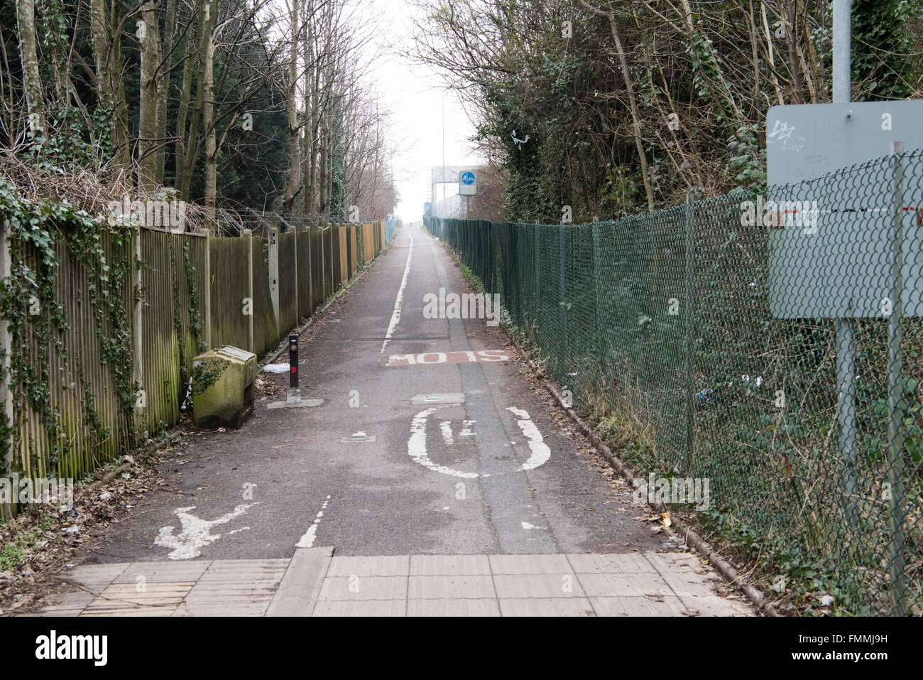 Rundown and unwelcoming cycle and footpath with high chainlink fencing and trees leading to the M5 Avonmouth bridge, England, UK Stock Photo