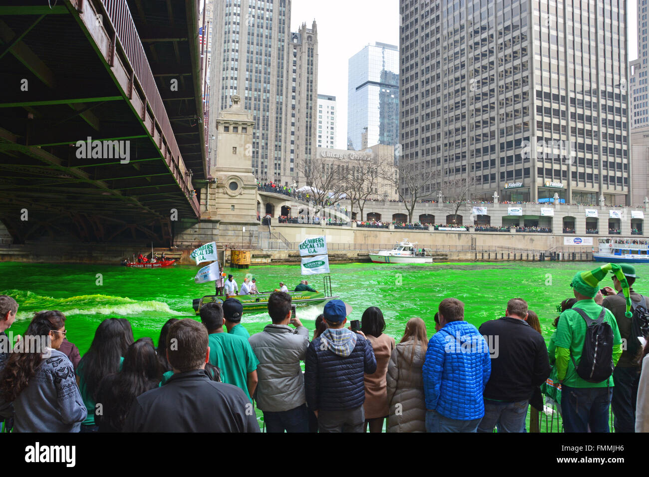 People watch from the bank as the Plumbers Union dyes the Chicago River green for St. Patrick's Day on March 12, 2016. Stock Photo