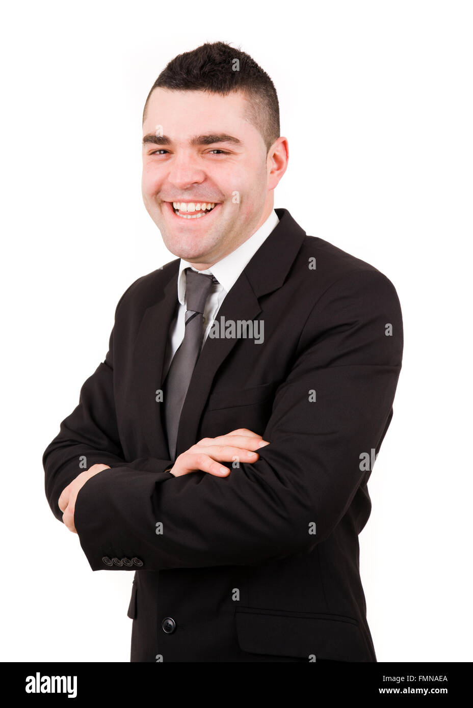 Portrait of a laughing young business man standing with arms crossed ...