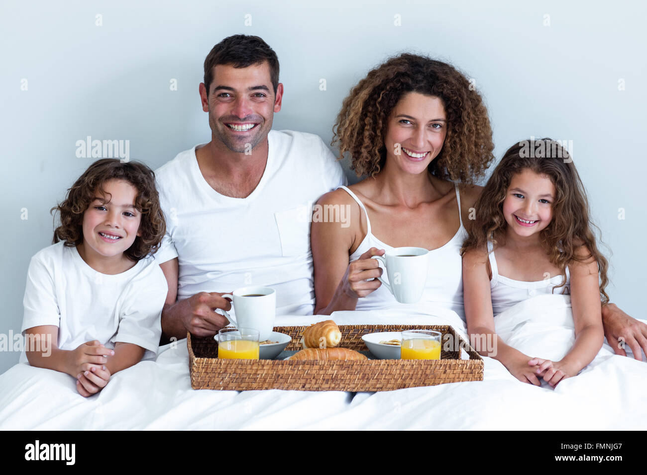 Portrait of a family sitting with breakfast tray in bed Stock Photo - Alamy