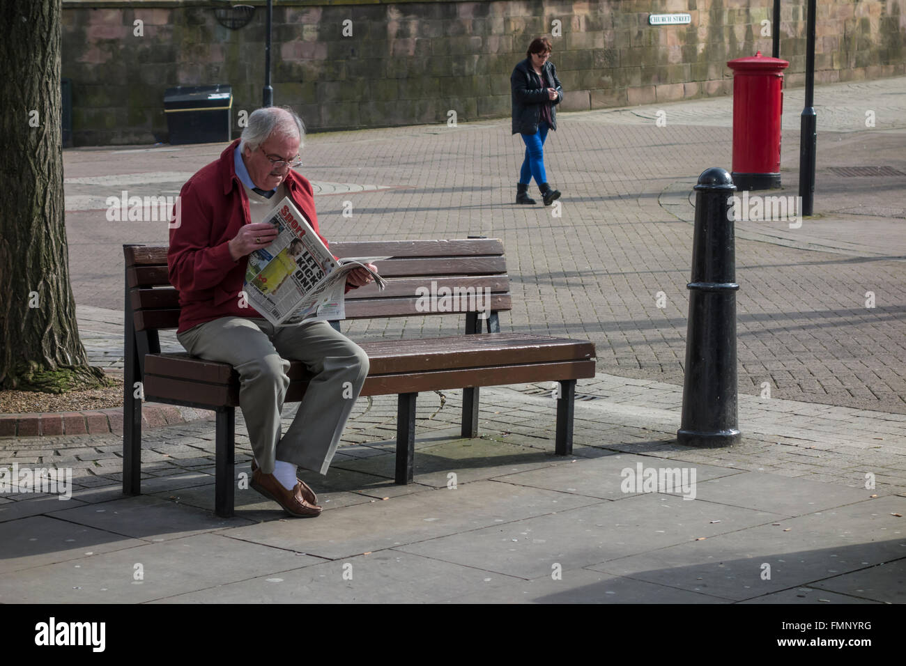 Elderly man sitting on bench reading newspaper Stock Photo - Alamy