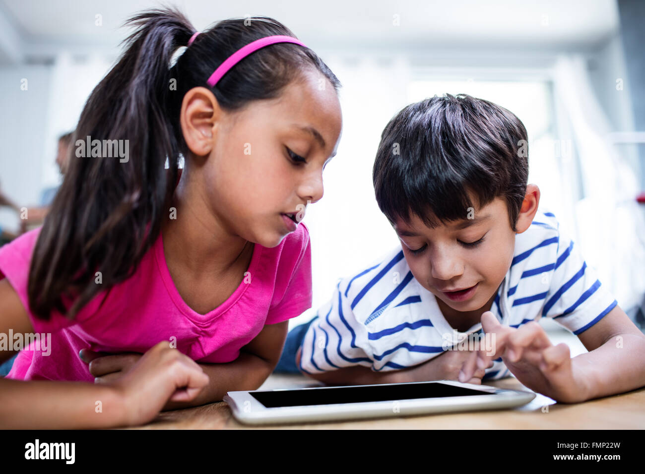 Brother and sister lying on floor and using digital tablet Stock Photo ...